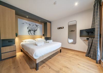 Un lit dans une chambre avec parquet et tableau au mur.
